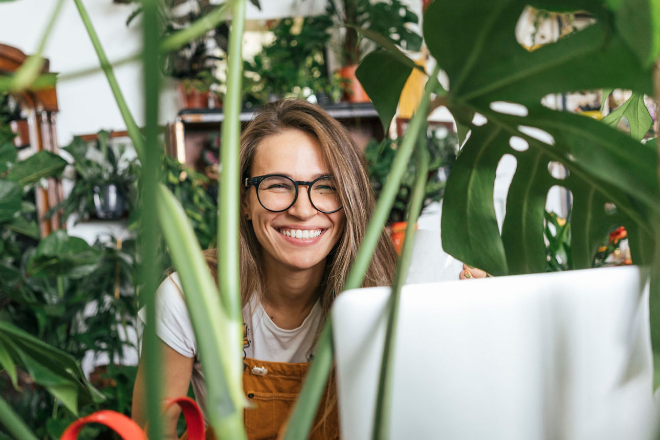 Eine junge sitzt am Schreibtisch umringt von Pflanzen