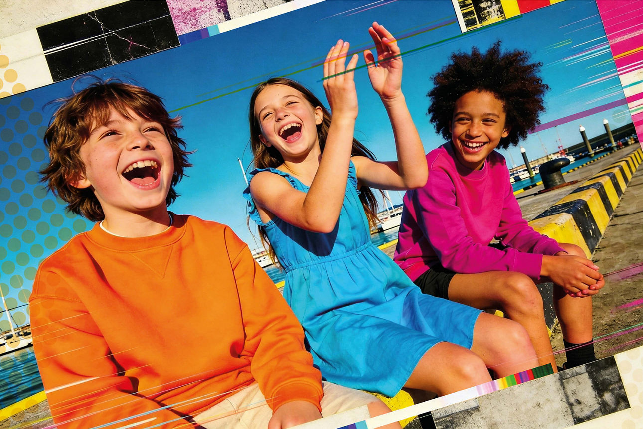 Drei Schüler sitzen ausgelassen im Freien nebeneinander.