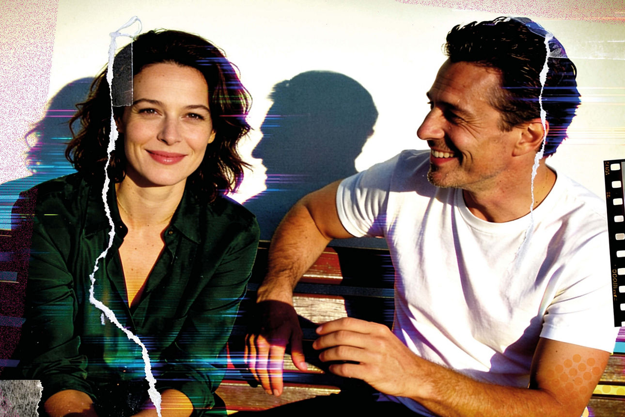 Ein Mann und eine Frau sitzen lächelnd nebeneinander. 