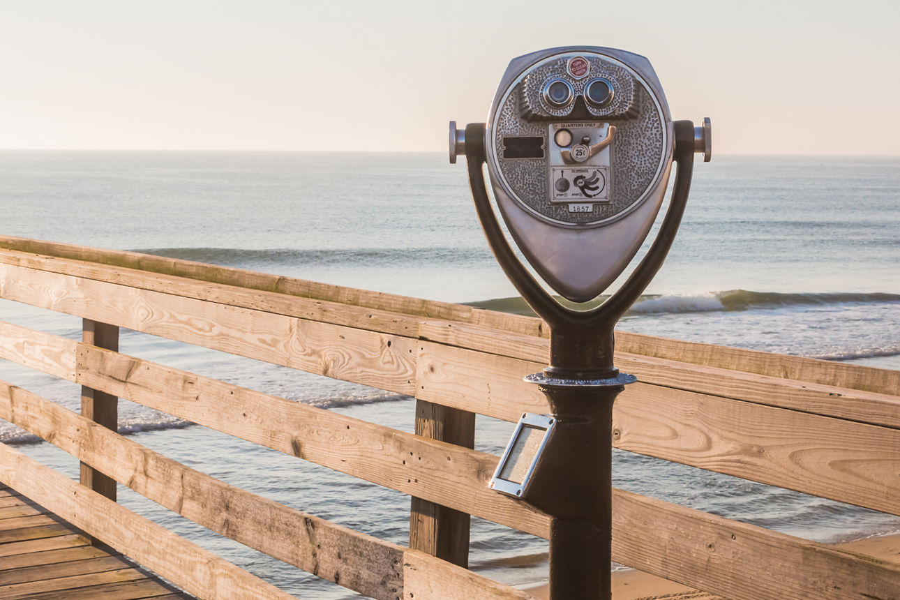 Ein stationäres Fernglas auf einem hölzernen Pier am Meer