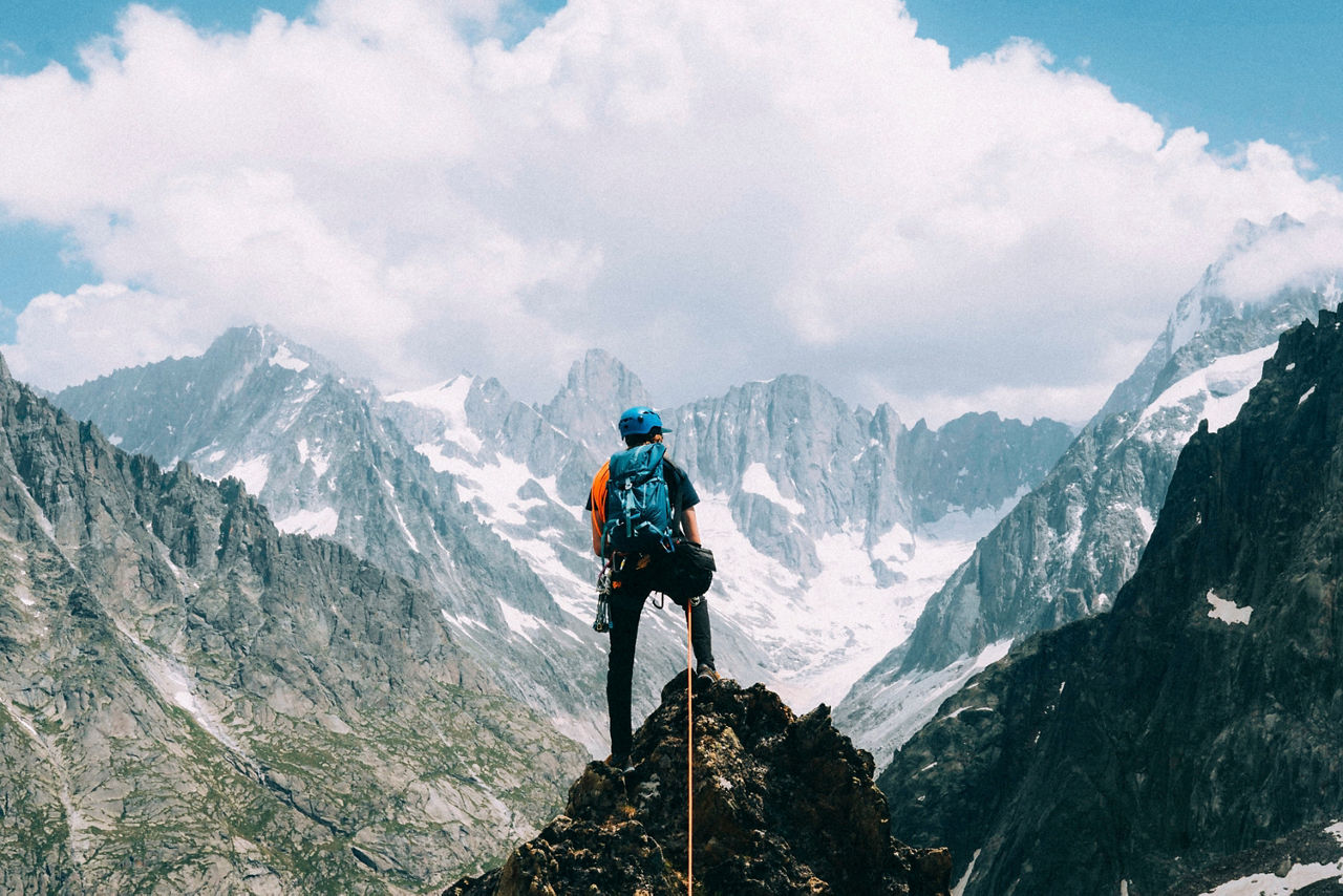 Ein Bergsteiger blickt auf Schneebedeckte Berge und genießt das Panorama.