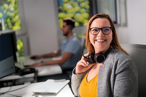Eine Frau sitzt an einem Schreibtisch und hat ein Headset auf