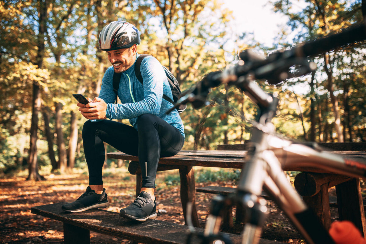 Radfahrer bei Pause am Smartphone in der Natur