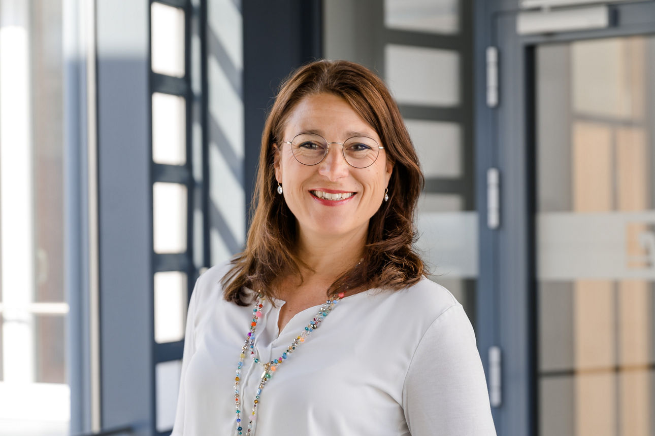 Portraitbild von Frau in weißer Bluse und dunklen Haaren.