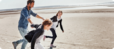 Ein Vater rennt mit seinen Kindern lachend und glücklich am Strand