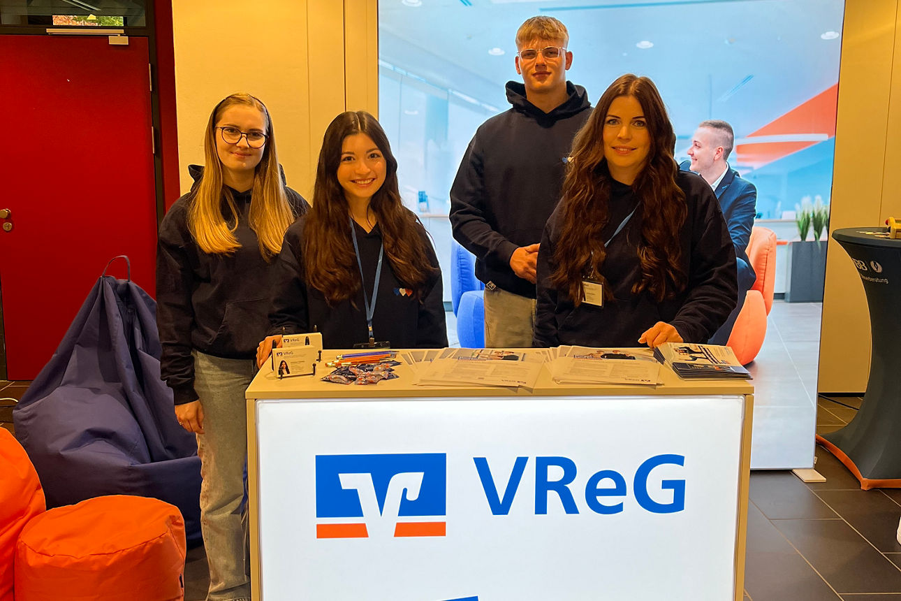 Vier junge Personen stehen nebeneinander im Messestand der VReG auf der Ausbildungsmesse in Ratzeburg.