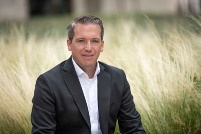 Arne Rautenberg, Portfoliomanger der Union Investment, steht im Anzug in einem Kornfeld