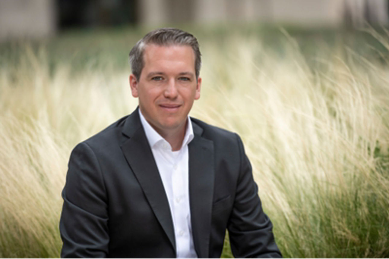 Arne Rautenberg, Portfoliomanger der Union Investment, steht im Anzug in einem Kornfeld