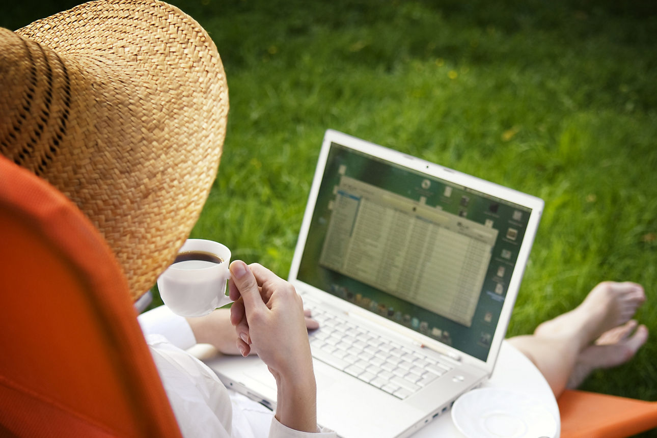 Frau sitzt im Liegestuhl und schaut auf einen Laptop