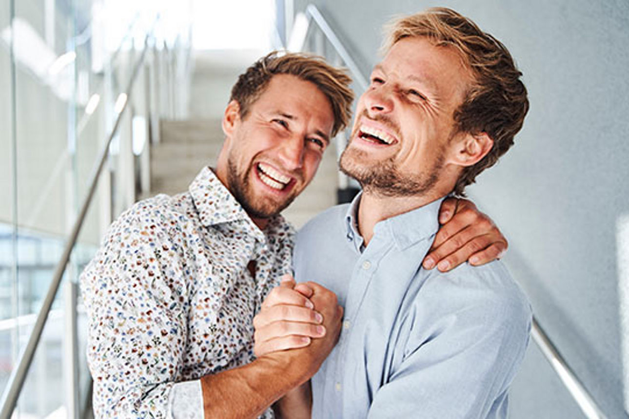 Zwei Männer, die sich lachend in den Armen liegen