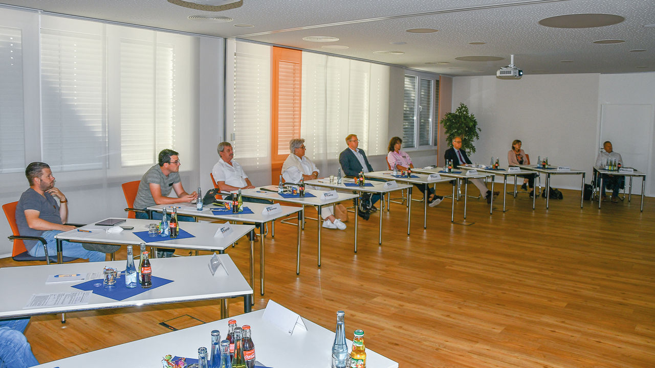 Mitglieder des Regionalbeirats sitzen an Tischen im Halbkreis in einem großen Raum