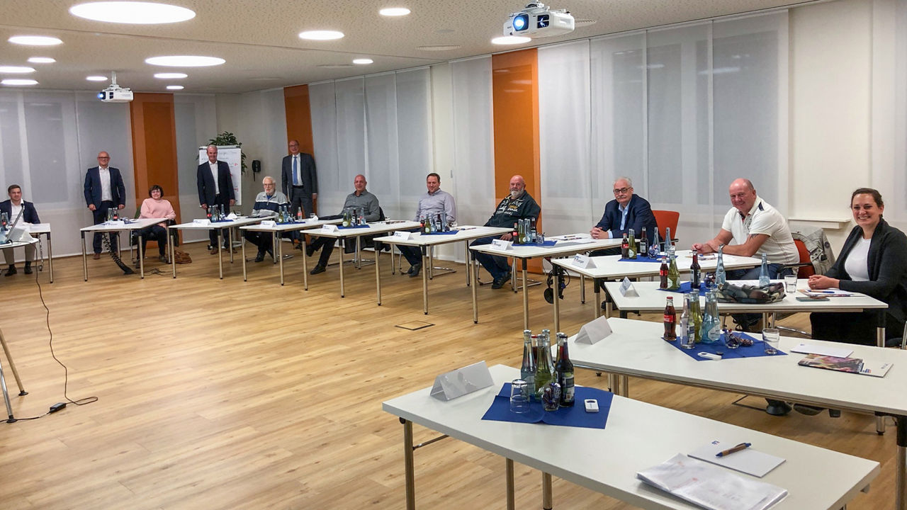 Mitglieder des Regionalbeirats sitzen an Tischen im Halbkreis in einem großen Raum