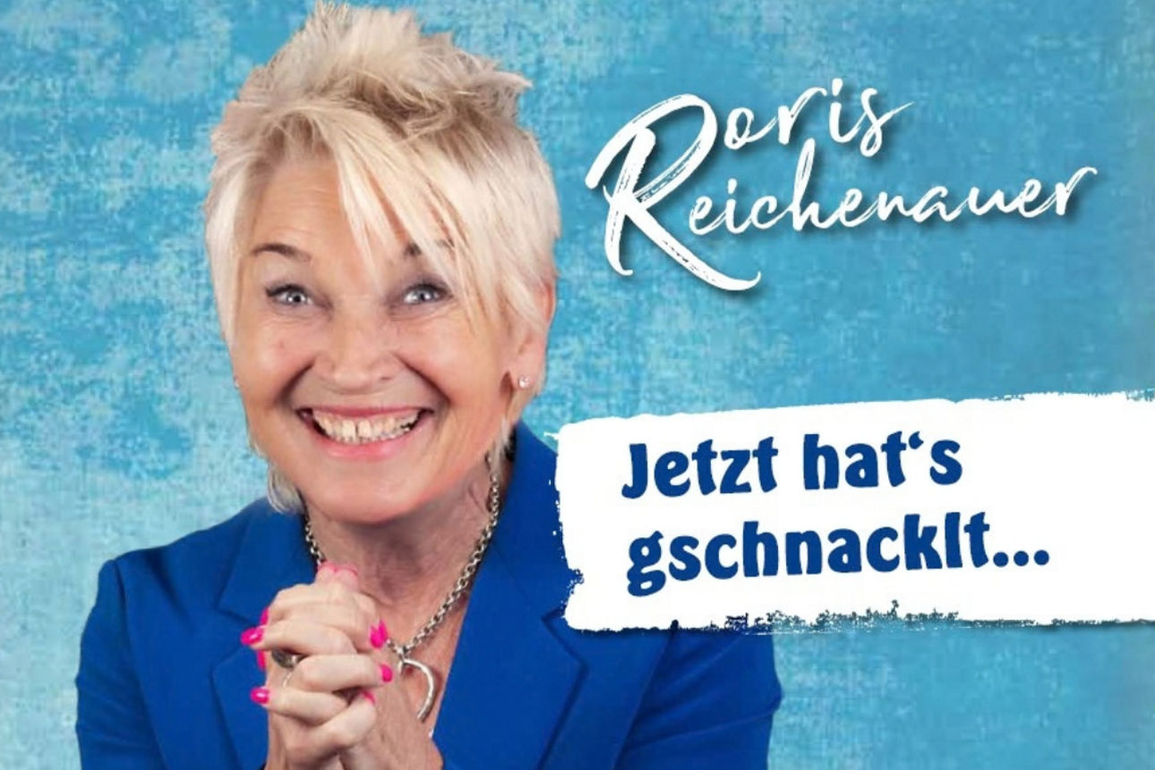 Person im blauen Blazer vor türkisfarbenem Hintergrund mit dem Schriftzug „Jetzt hat's gschnacklt...“.