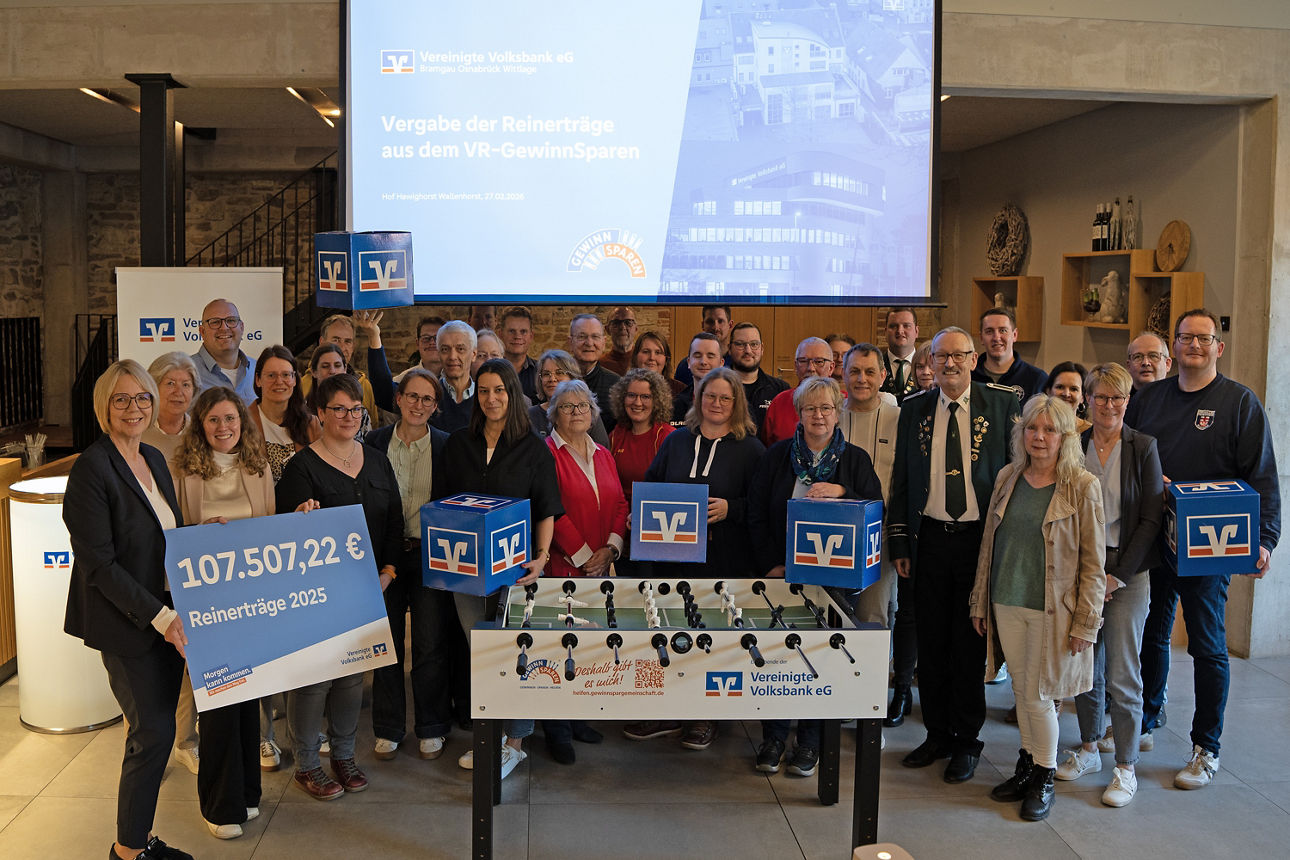 Eine Gruppe von Menschen vor einer Leinwand mit einem großen Scheck. 