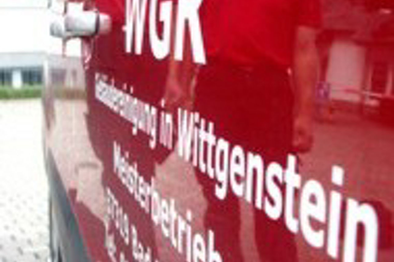 Glänzend rote Seite eines Fahrzeugs mit weißer Aufschrift