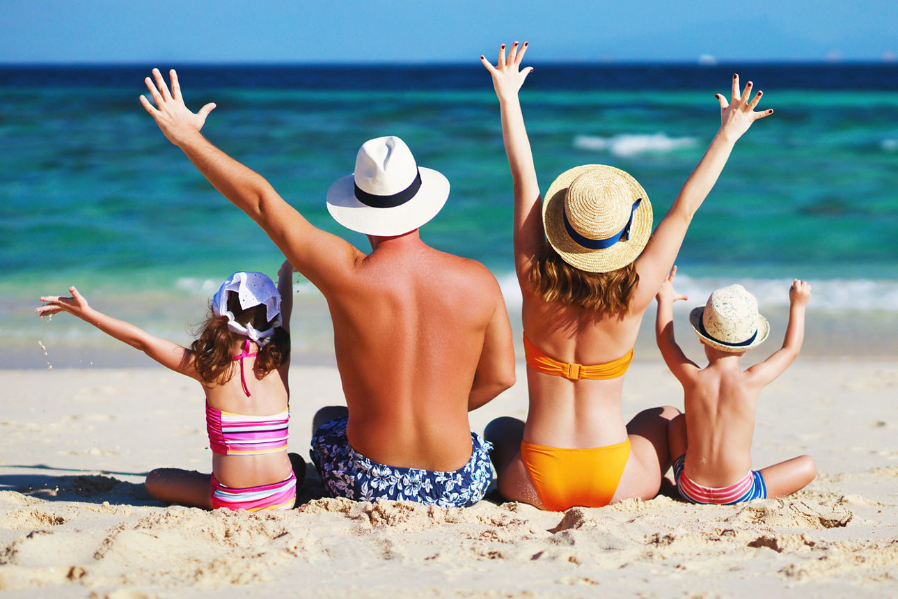 Glückliche Familie: Vater, Mutter und Kinder mit dem Rücken zur See am Strand
