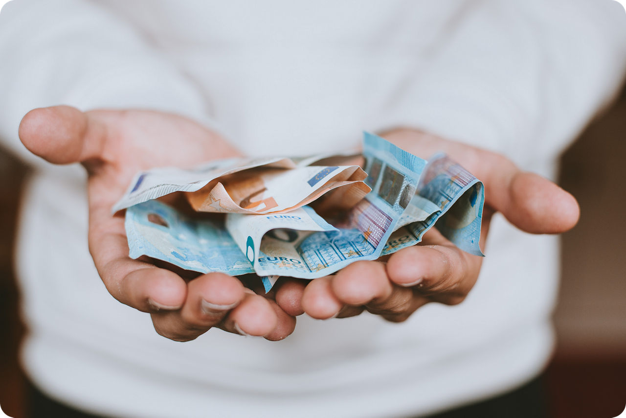 Offene Handflächen auf der verschiedene Euro-Scheine liegen