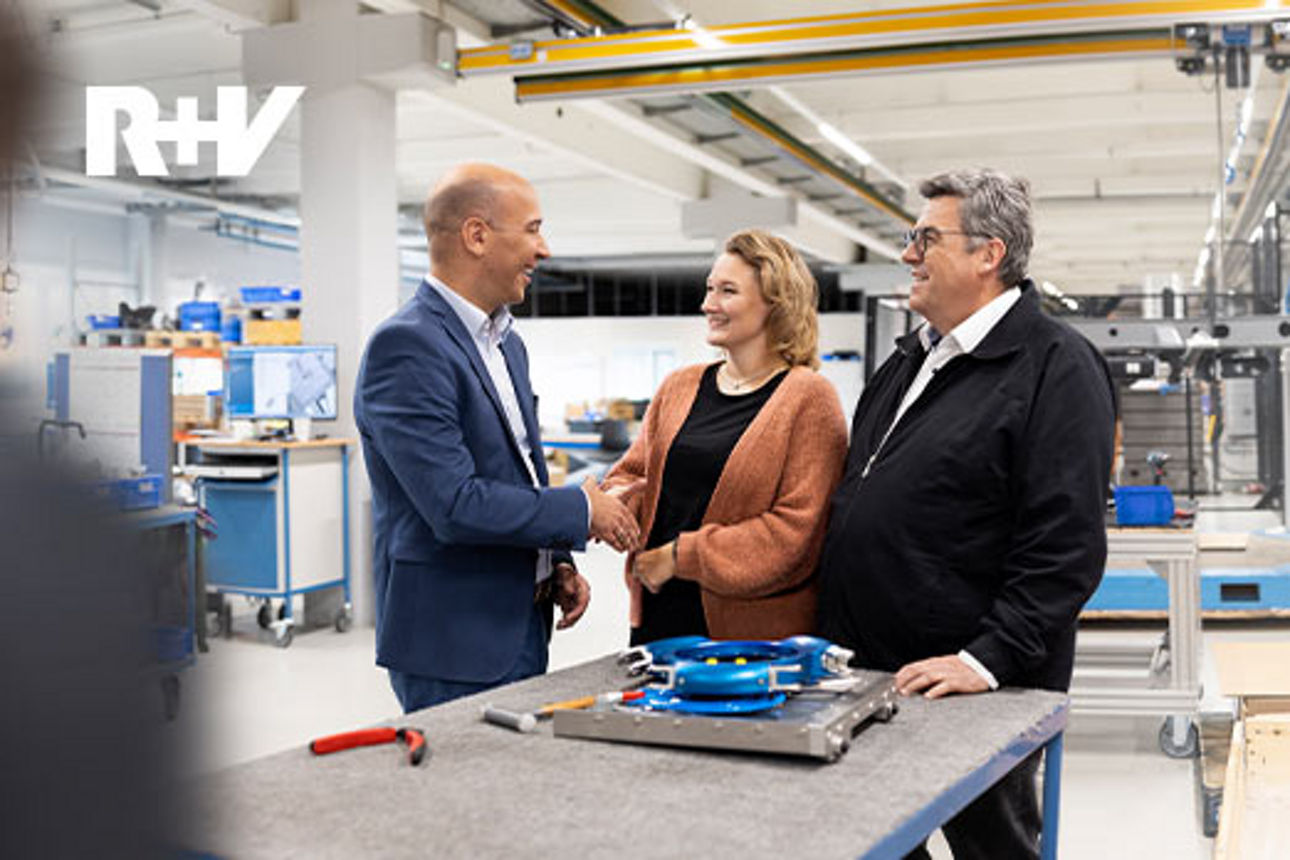 Eine Frau und zwei Männer stehen in einer Produktionshalle