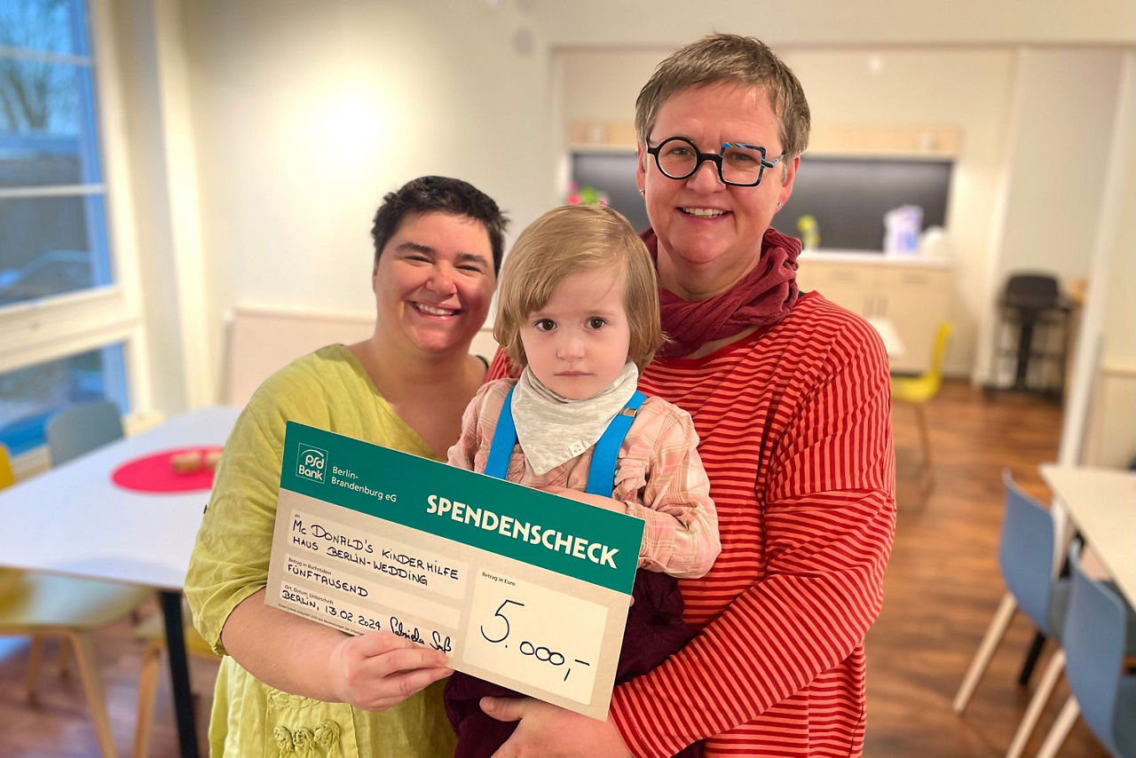 Glückliche Familie hält Spendenscheck in die Kamera