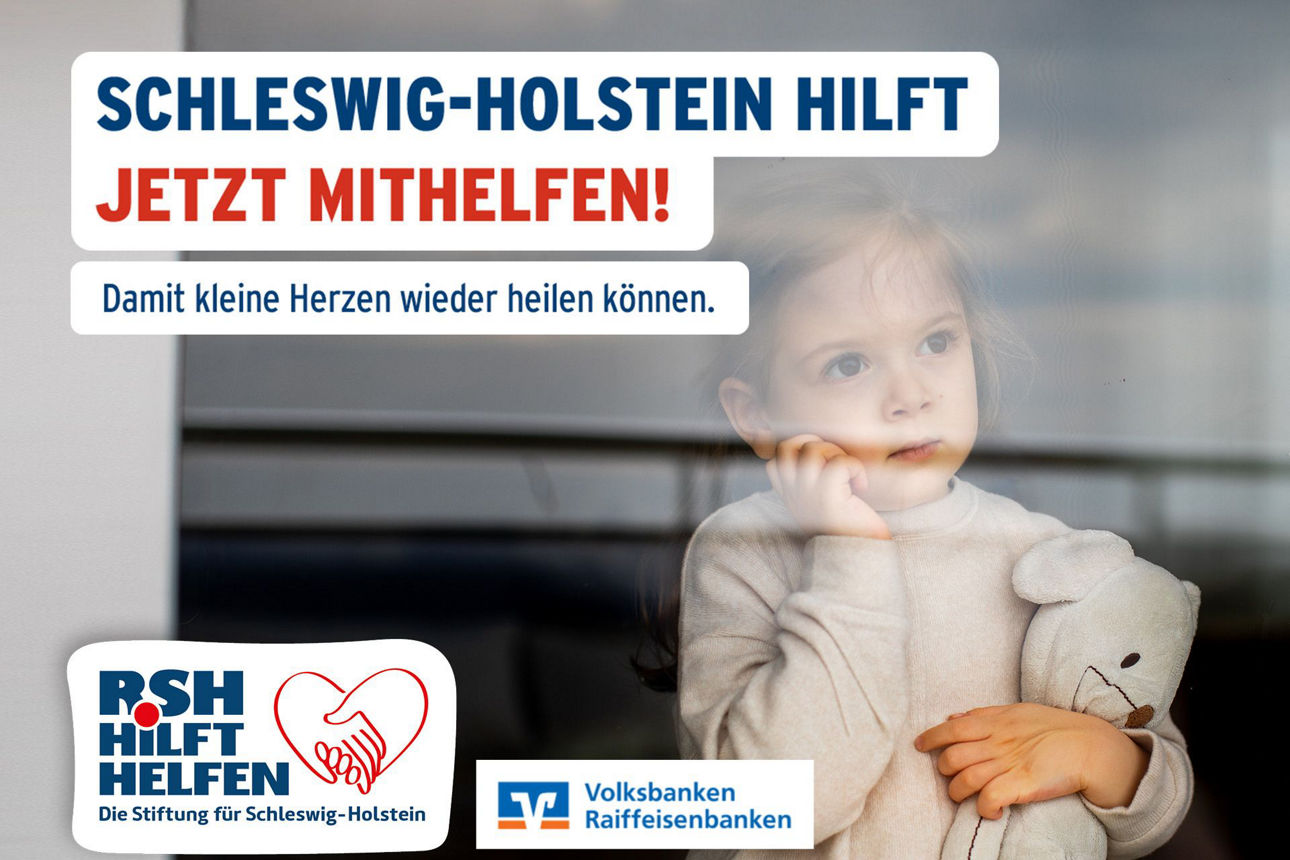 Ein kleines Mädchen steht mit einem Teddy im Arm am Fenster und blickt nachdenklich hinaus.