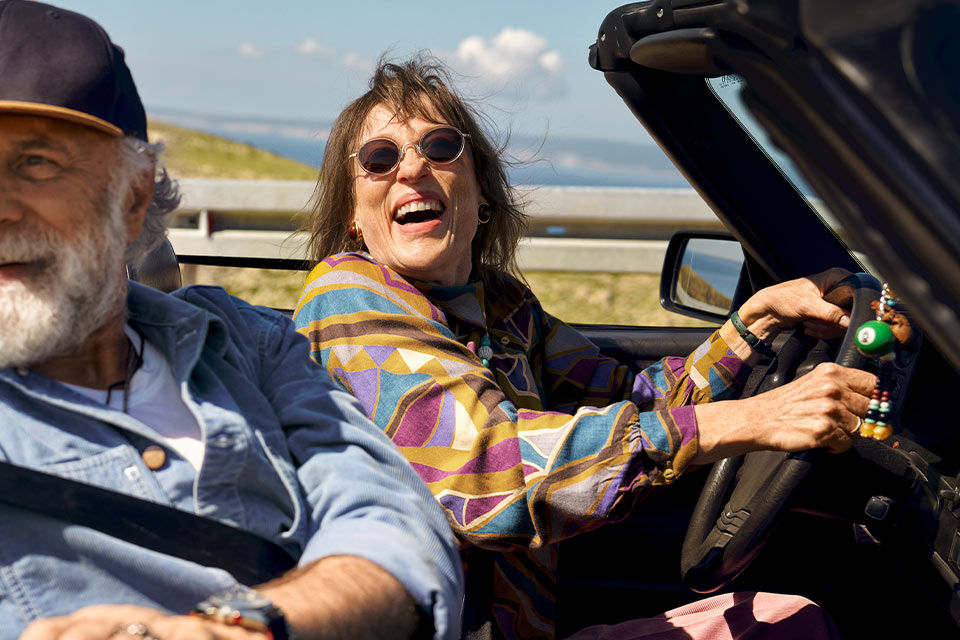 Lachendes Rentnerpaar in einem Cabrio