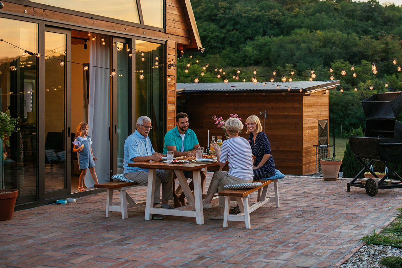 Familie sitzt auf der Terasse beim Essen.