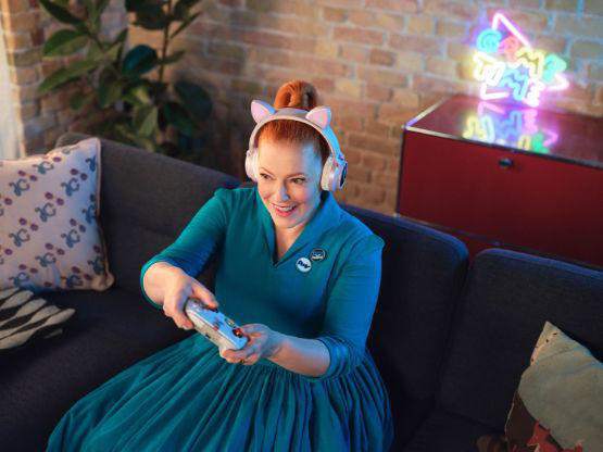 Frau sitzt auf der Couch und spielt mit einem Controller