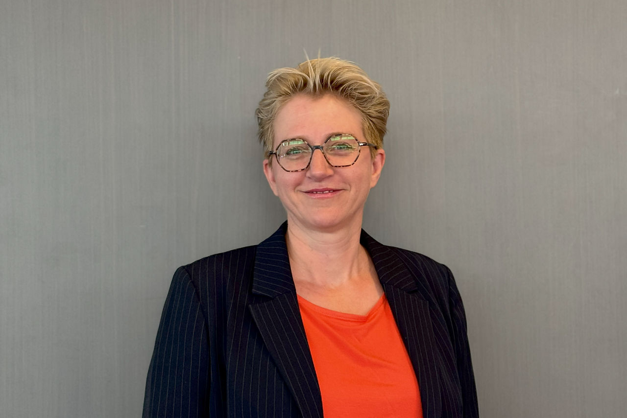 Blonde, kurzhaarige Frau mit rotem T-Shirt und scharzem Blazer
