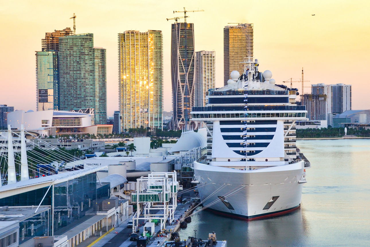 Nachhaltiger anstoßen: Wie Saltwater's Kreuzfahrten leichter macht Großes Kreuzfahrtschiff im Hafen vor moderner Skyline mit Hochhäusern.