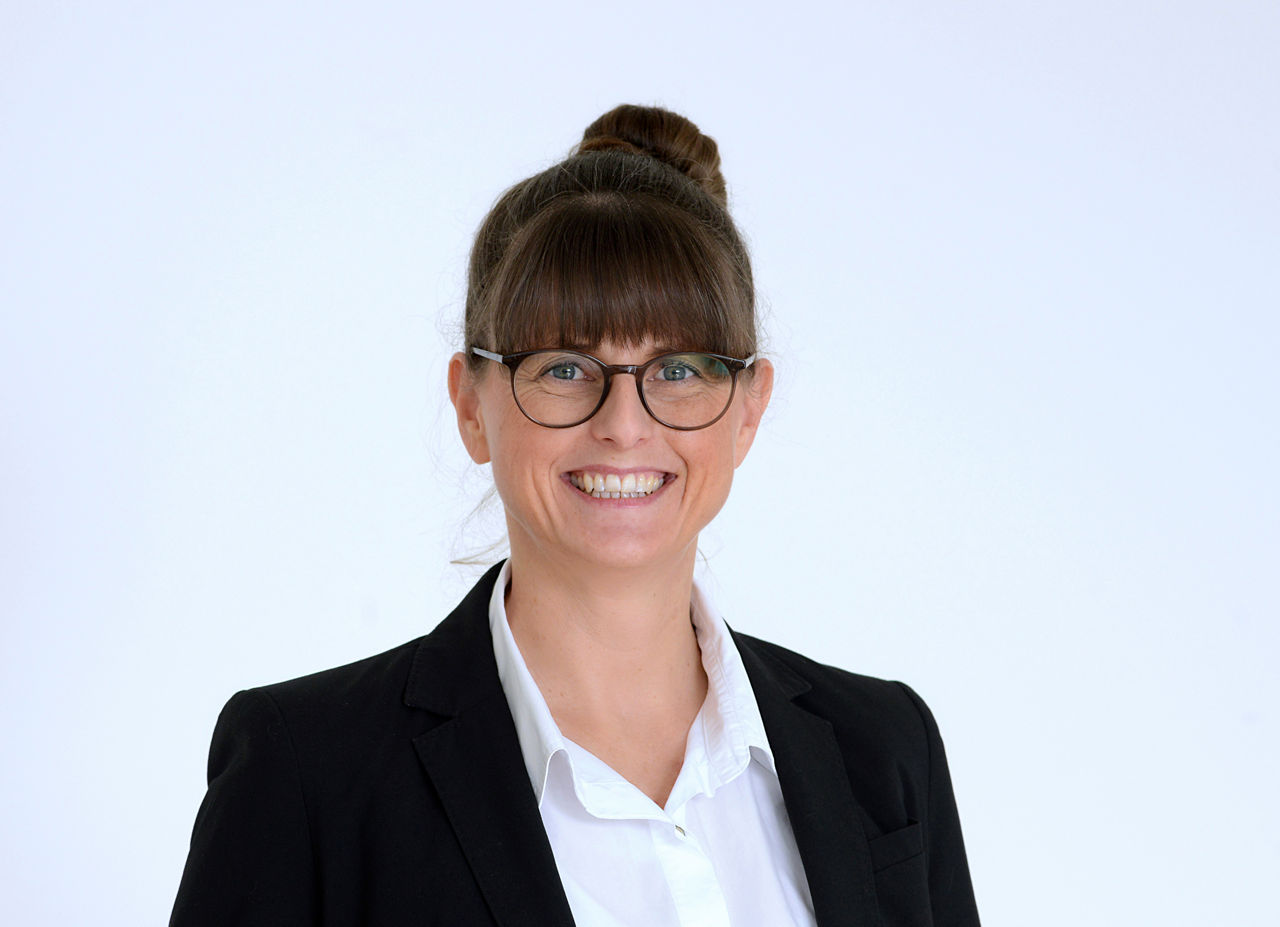 Geschäftskundenberaterin Sandra Gerke vor grauem Hintergrund