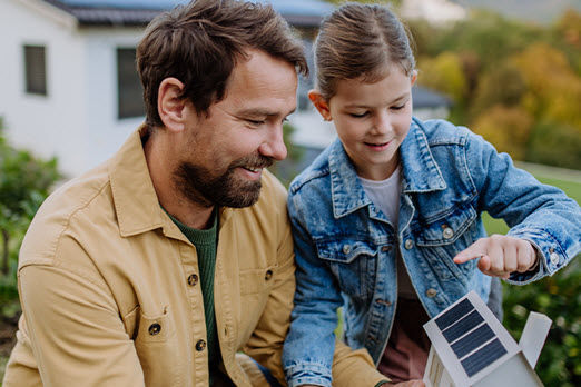 Ein Mann und eine Frau halten ein Maßband auf dem Boden und ein Hund schaut dabei zu