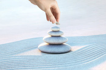 Eine Hand stapelt Steine im Sand