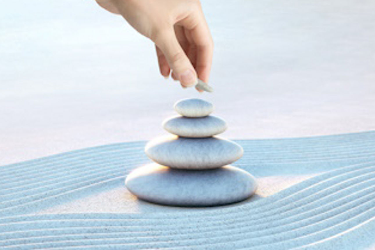 Eine Hand stapelt Steine im Sand