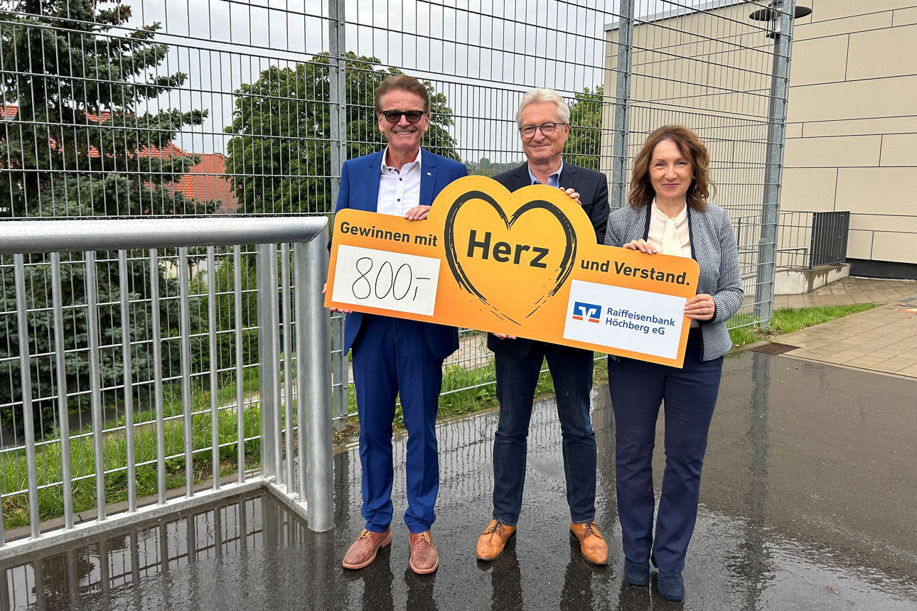 Drei Personen vor einem Tor mit einem Scheck über 800 Euro. 