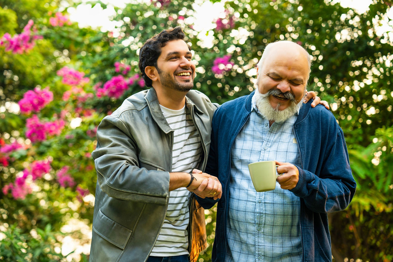  Vater und Sohn im Garten im Gespräch über Vermögensübergabe und Schenkungen in der Familie.
