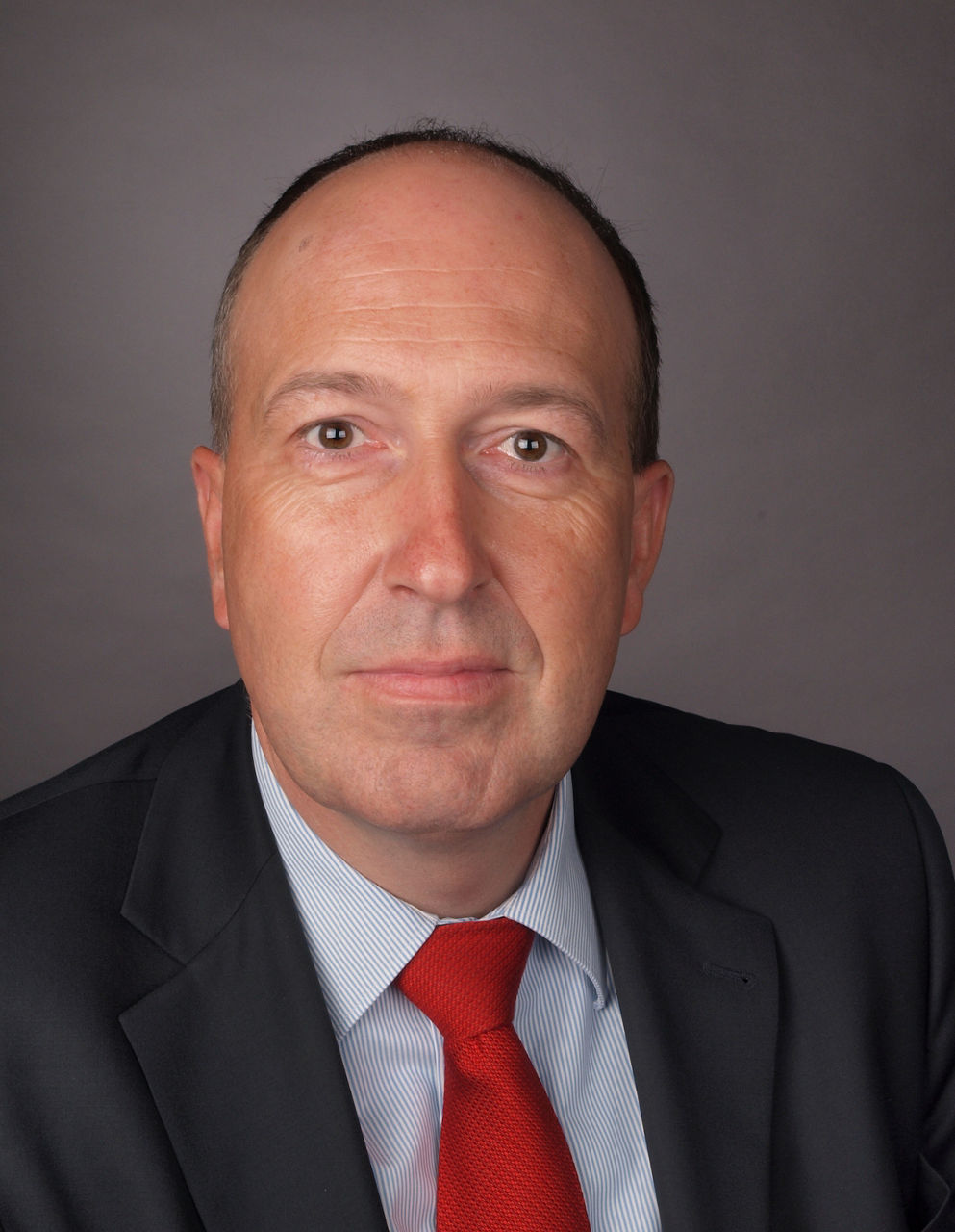 OLYMPUS DIGITaMitarbeiter der Bank im Anzug mit roter Krawatte lächelt in die Kamera.AL CAMERA