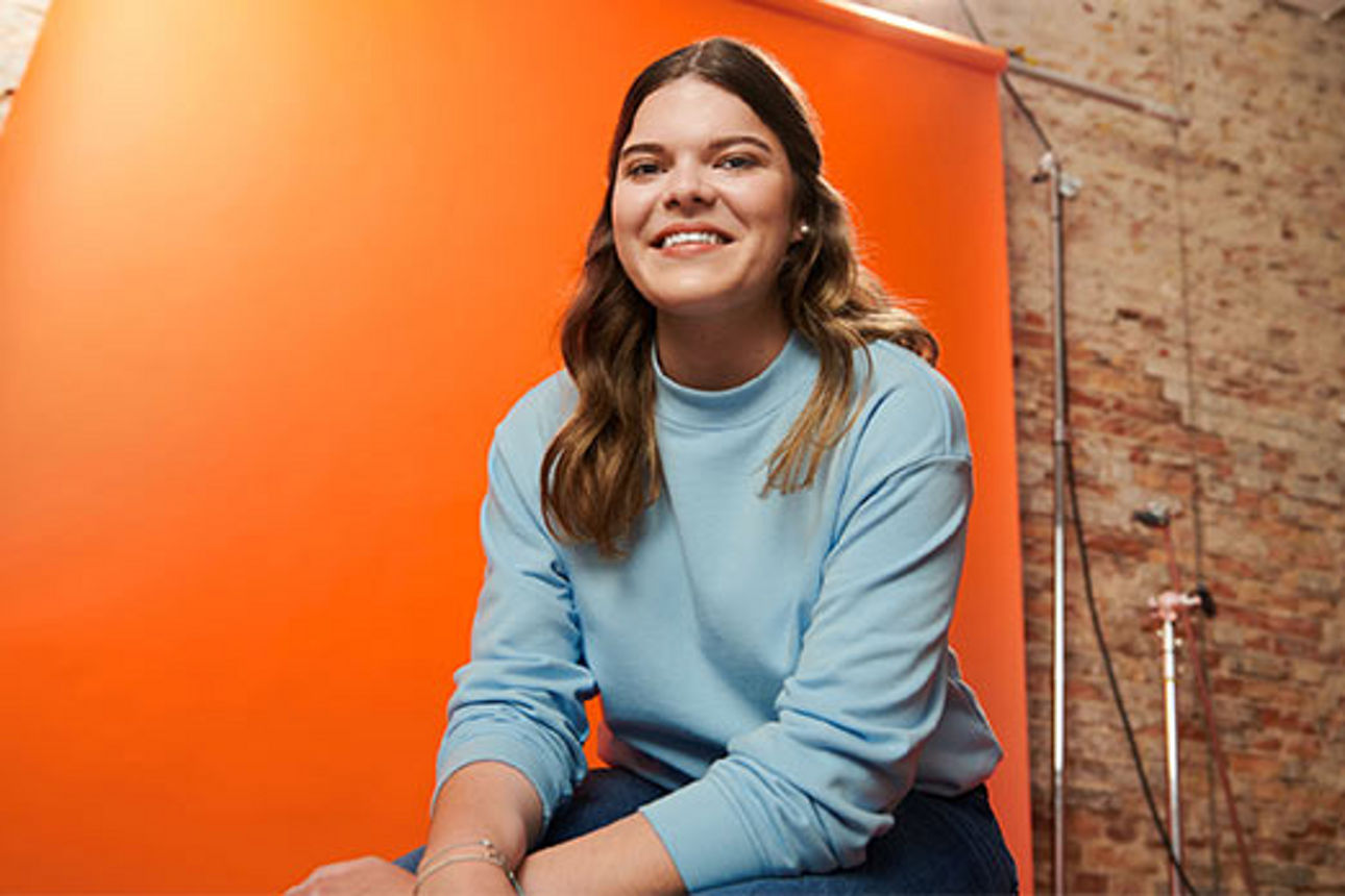 Ein Mädchen vor einer orangefarbenen Leinwand