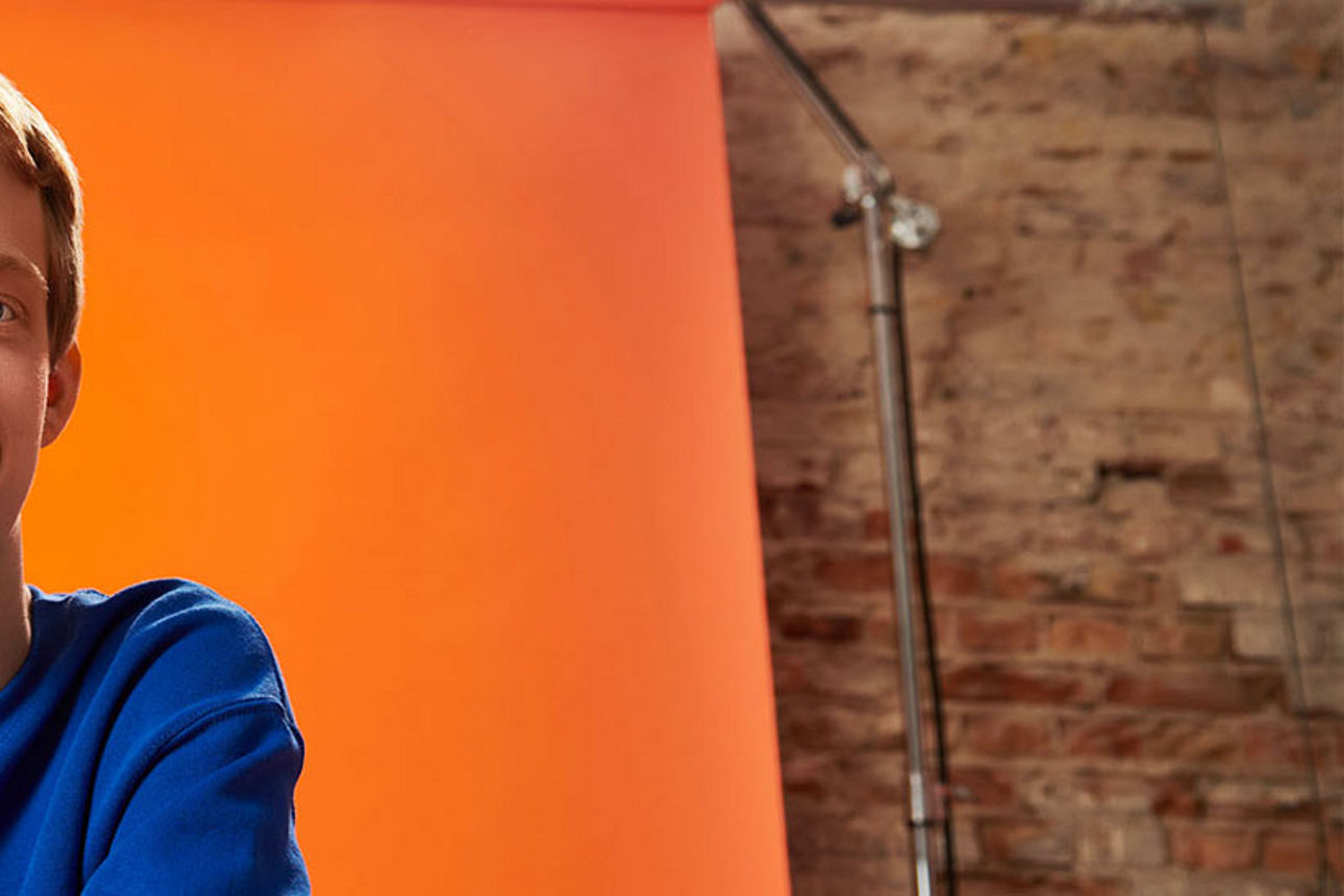 Praktikant beim Videodreh vor einer Leinwand