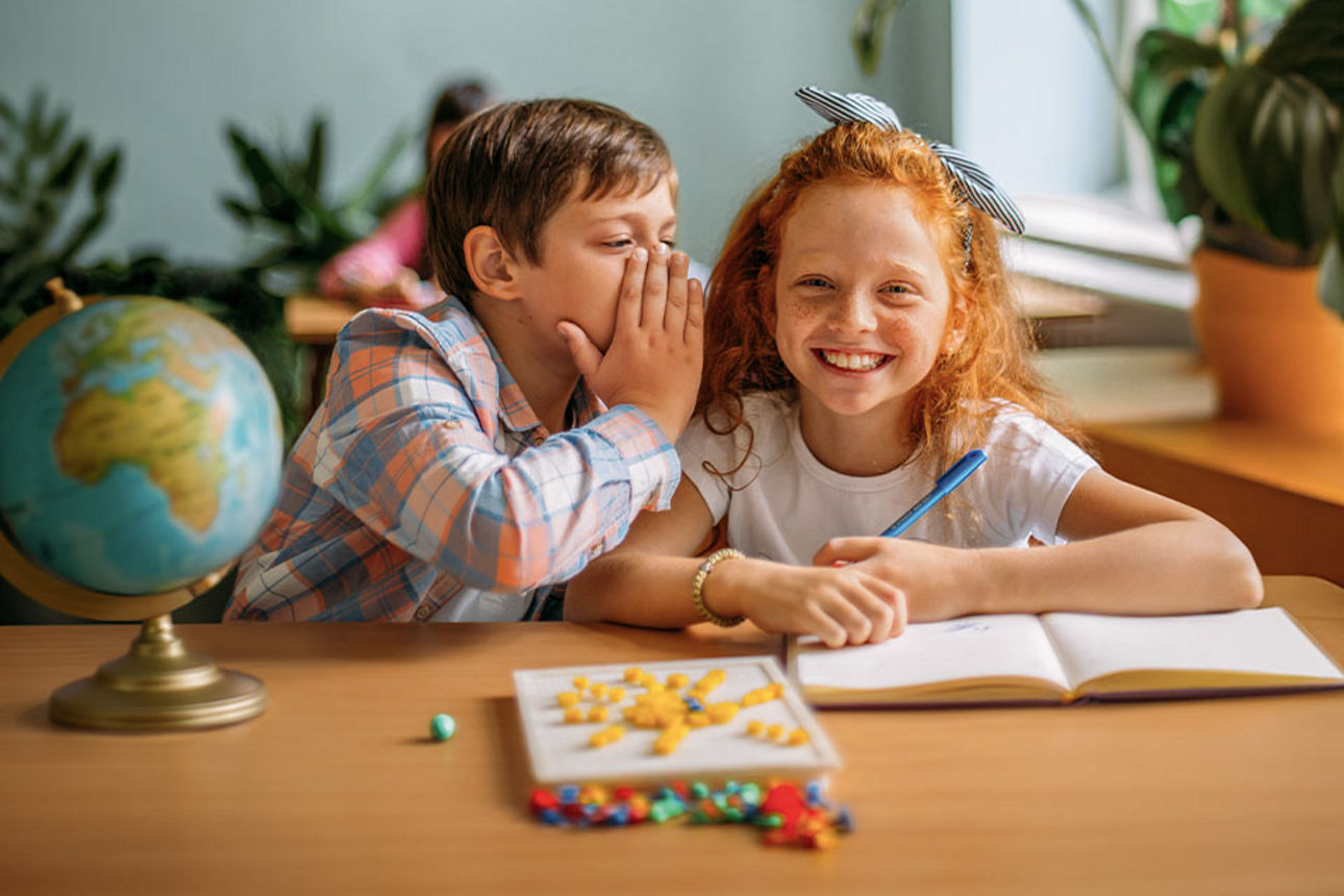 Schüler flüstern sich etwas ins Ohr