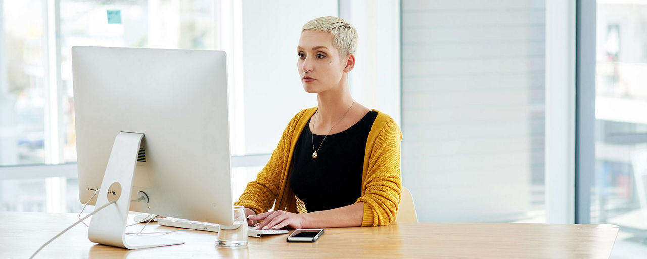 Frau sitzt an einem Tisch vor ihrem Computer