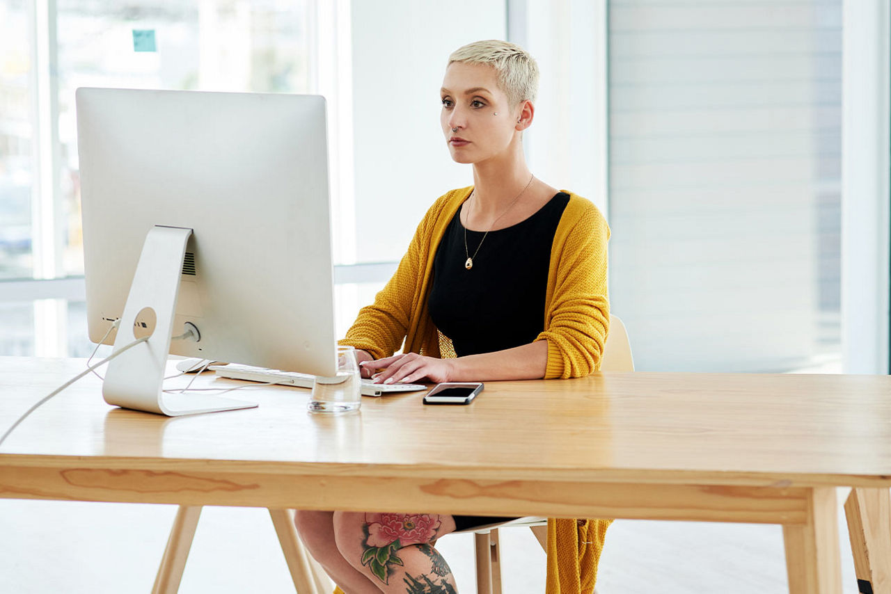 Frau sitzt an einem Tisch vor ihrem Computer