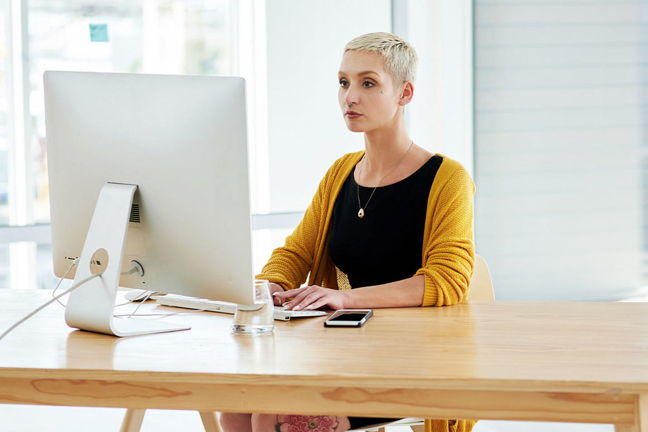 Frau sitzt an einem Tisch vor ihrem Computer