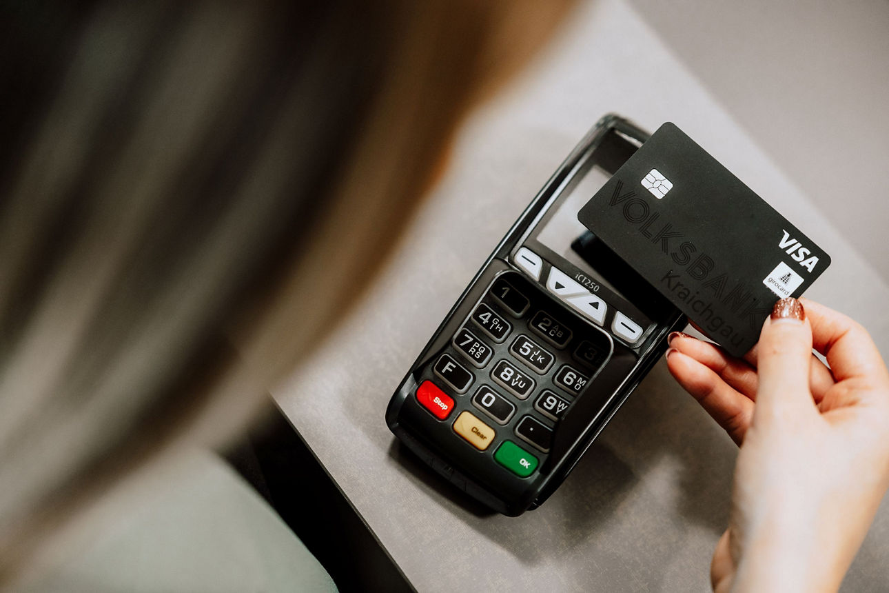 Frau bezahlt mit schwarzer girocard an einem Kartenterminal.