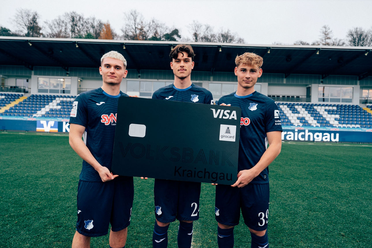 Drei Fußballspieler halten eine übergroße schwarze girocard mit der Aufschrift Volksbank Kraichgau.