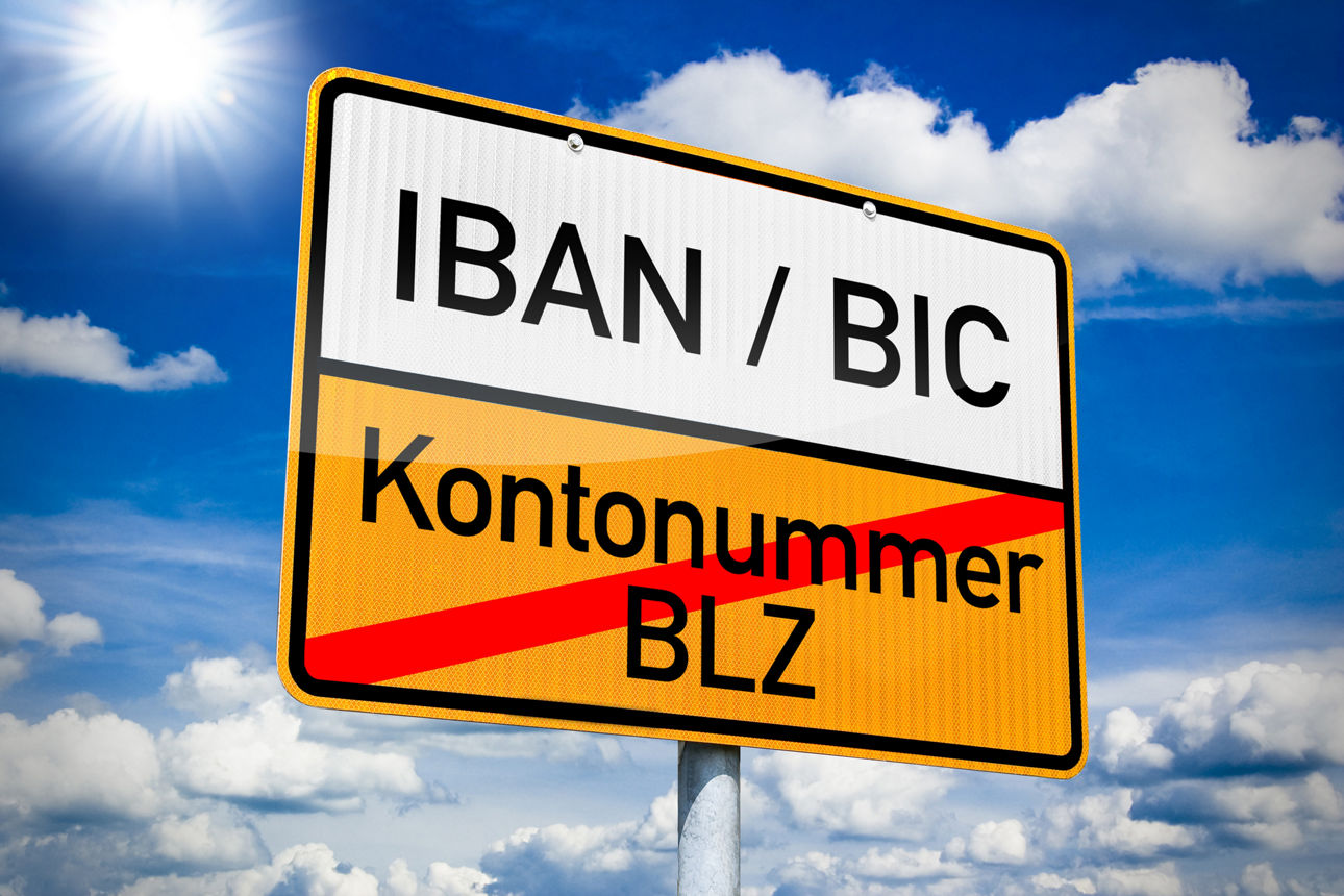 Ein Straßenschild auf dem IBAN / BIC geschrieben ist und Kontonummer / BLZ durchgestichen ist. 