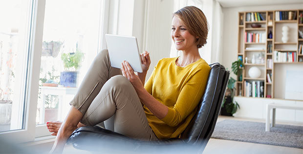 Frau mit Laptop sitzt im Sessel