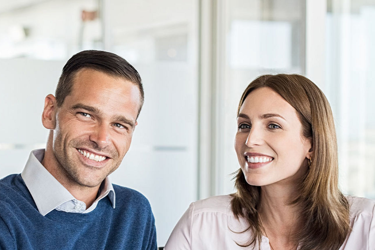 Mann und Frau lächelnd im Gespräch mit ihrem Berater