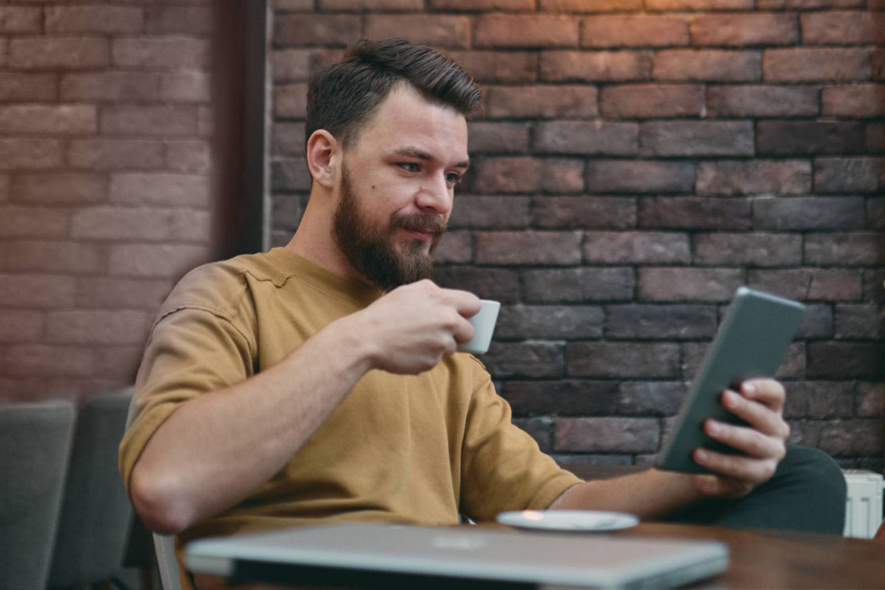 Junger Mann im Kaffee mit Tablet in der Hand