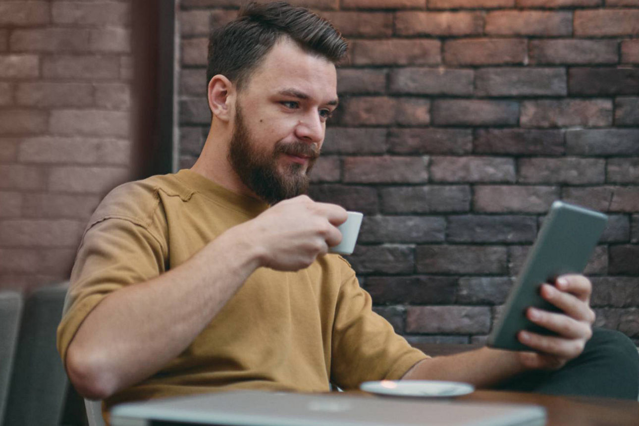 Junger Mann im Kaffee mit Tablet in der Hand