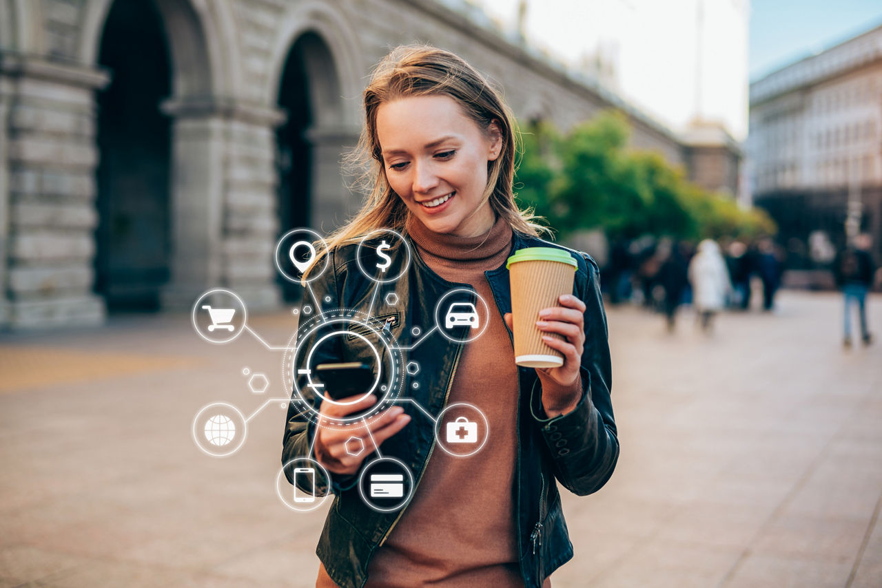 Schöne junge Frau, die ein Smartphone mit verschiedenen Symbolen intelligenter Technologie verwendet.